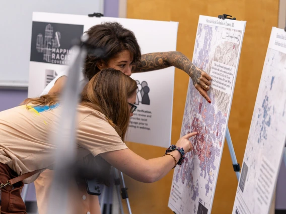 two people pointing at a posted board with a map on it