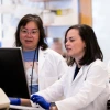 Zelieann Craig looking at a computer monitor in a lab while wearing a lab coat